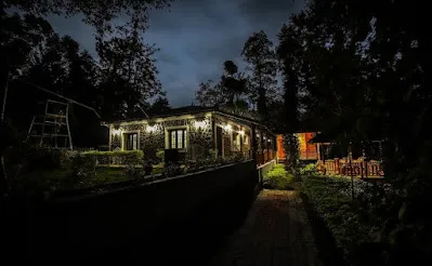 Warm lights along the Stone Villa beside a garden path at night
