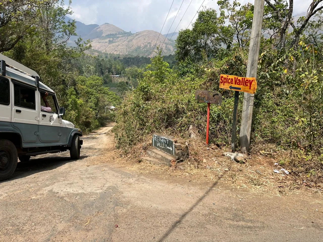 Hand-painted Spice Valley and Elephant Valley signboards beside an unpaved road, with hills behind