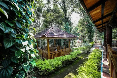 The wooden dining gazebo among clipped hedges and trees, seen from the villa verandah