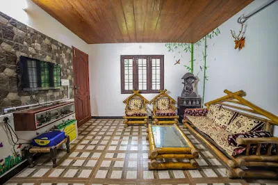 Living hall of the Stone Villa with a stone feature wall, timber ceiling and bamboo furniture