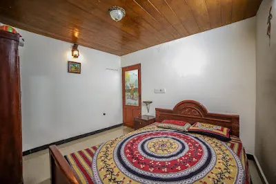 Another view of Stone Villa Room 1, with a carved wooden bed and a wall lamp