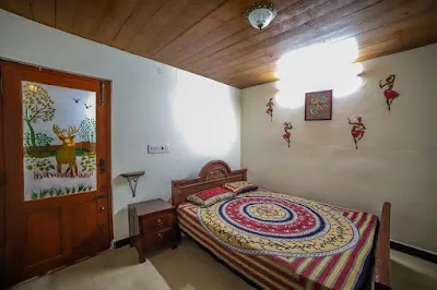 Stone Villa Room 1: a double bed with a mandala bedspread and a door painted with a deer