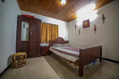 Stone Villa Room 2 with a carved wardrobe, a wooden bed and golden curtains